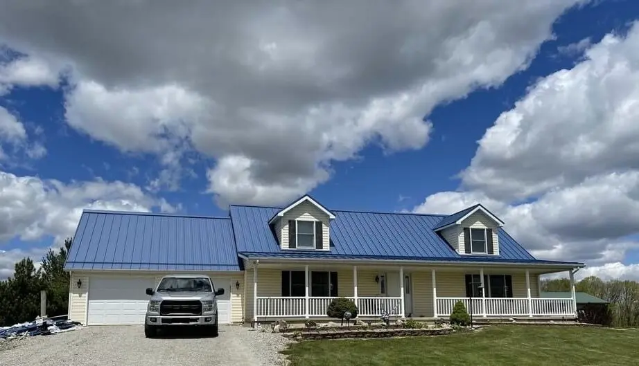 Blue standing seam metal roof on country home with wrap-around porch