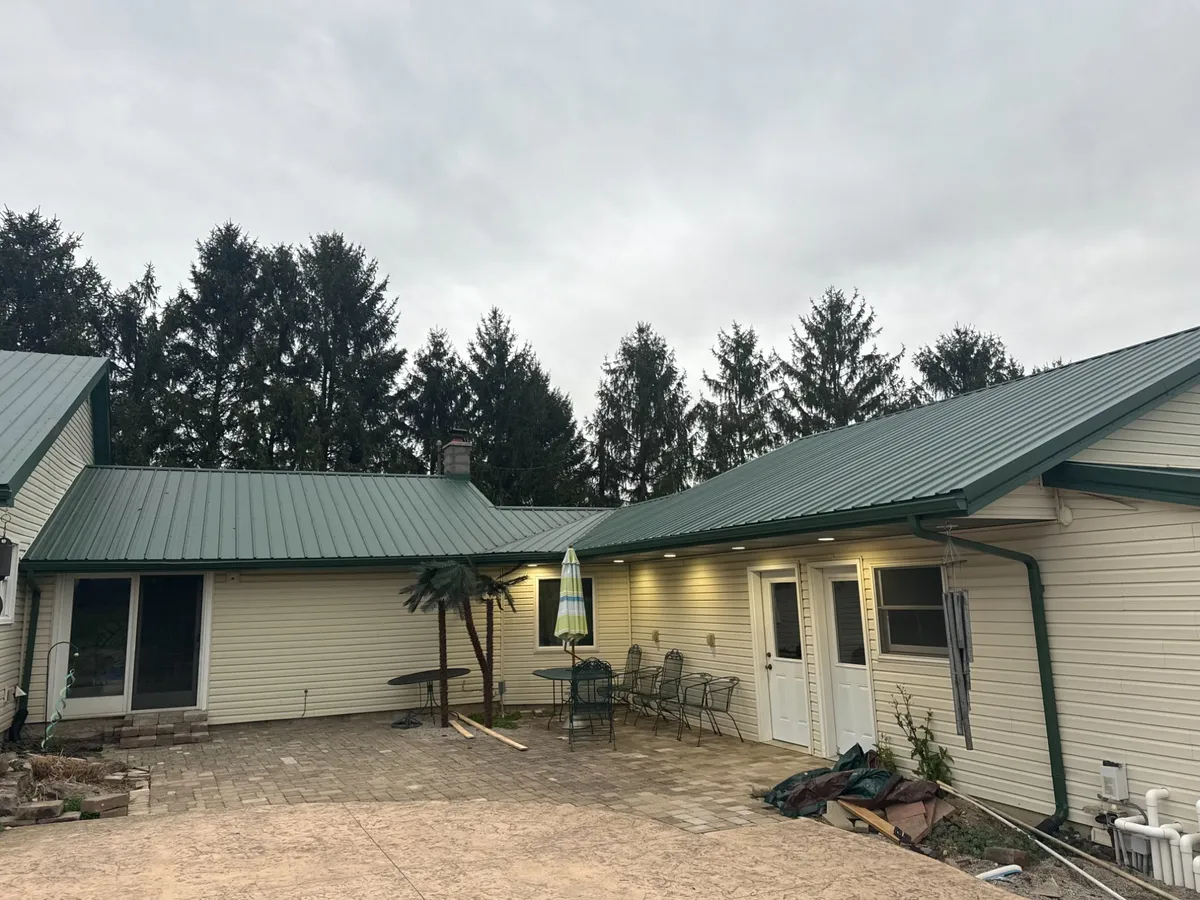 Green standing seam metal roof on residential home with patio area